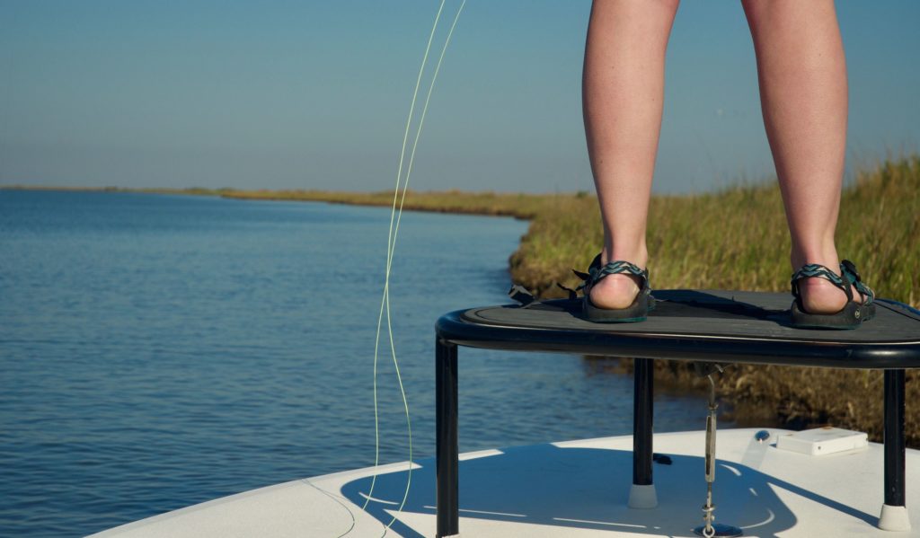 Woman standing on a boat fly fishing 